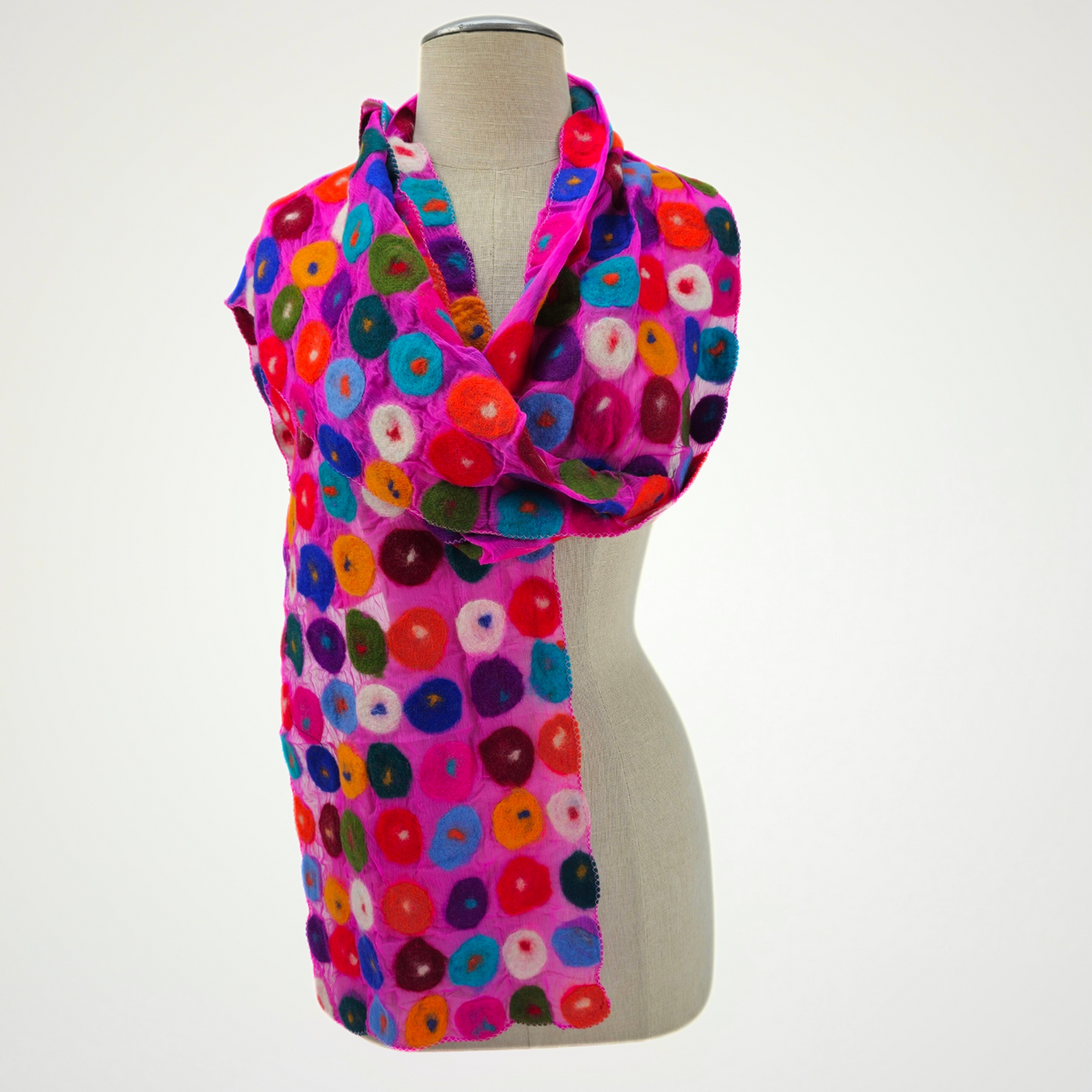 fuchsia scarf covered with multicolored circle motifs, wrapped around a mannequin
