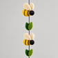 Detail of two yellow and black wool bees and green felt leaves