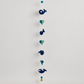Full handmade navy whale and teal heart wool garland with bell on warm gray