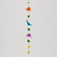 Full handmade wool dinosaur garland with green leaves and bell on warm gray