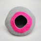 Gray handmade wool cat cave with bright pink entrance on warm gray background.