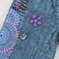 Purple flower applique and embroidered vine detail on blue cotton
