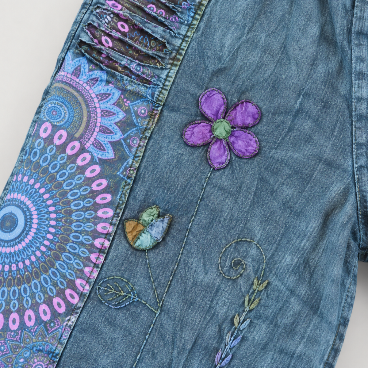 Purple flower applique and embroidered vine detail on blue cotton