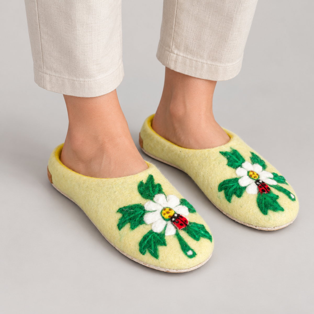 Model wearing yellow daisy and ladybug wool slippers