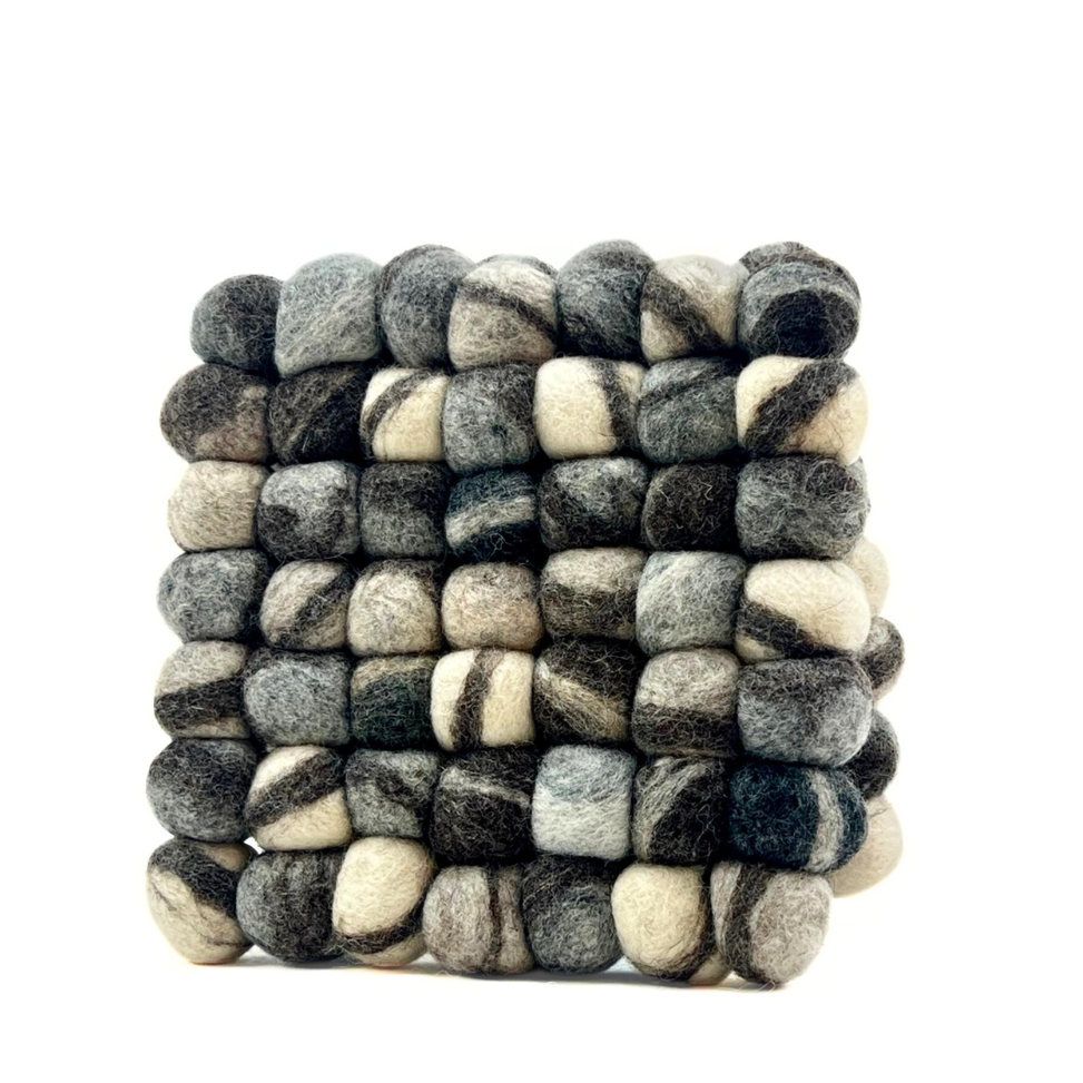 Stone-colored wool trivet with handmade felt balls in gray, charcoal, and cream