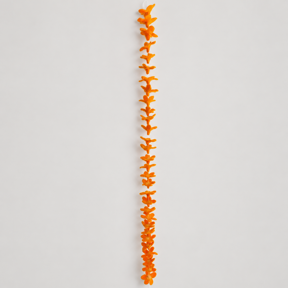 Full-length orange wool flower garland on warm gray
