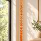 Orange wool flower garland displayed beside a window