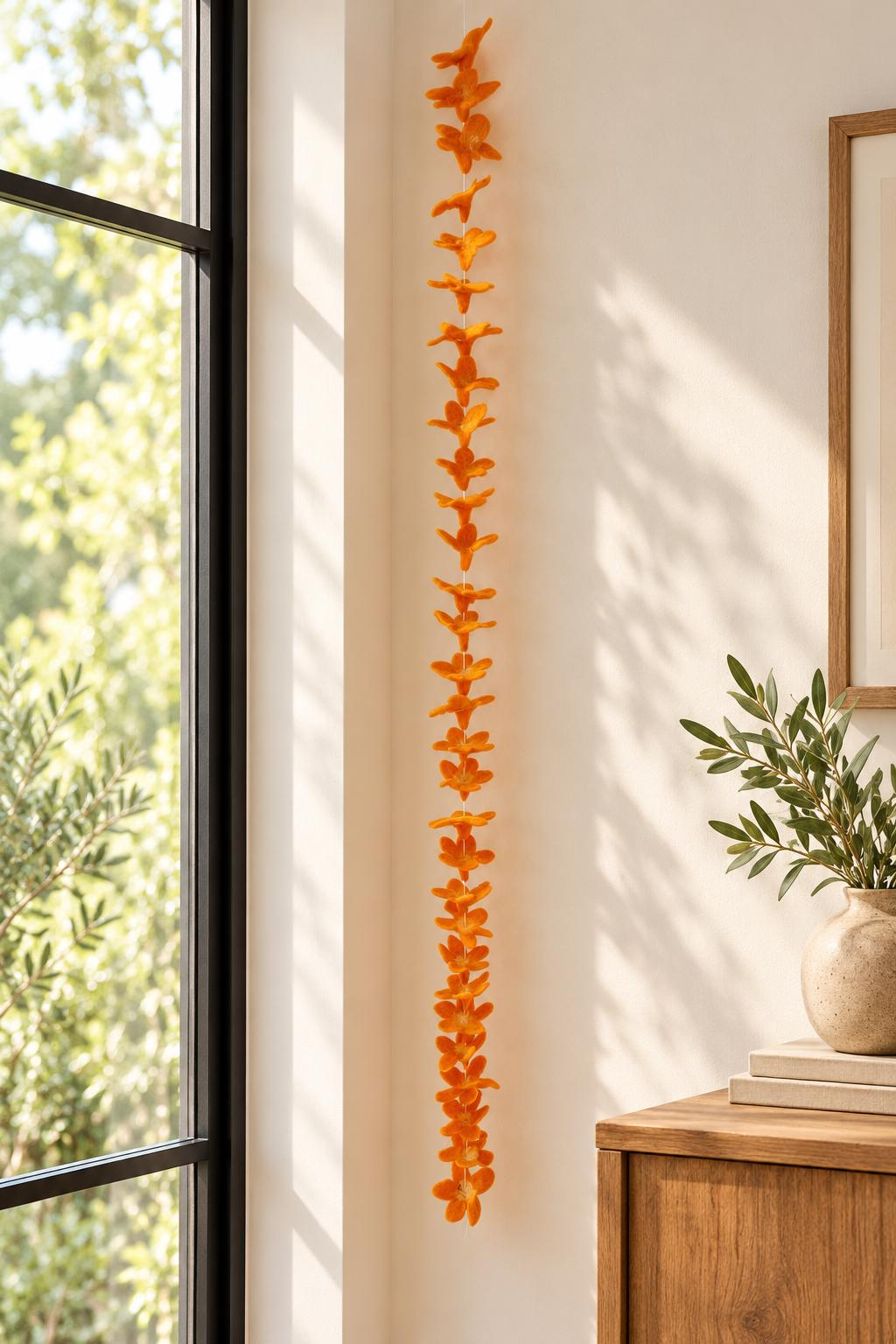Orange wool flower garland displayed beside a window