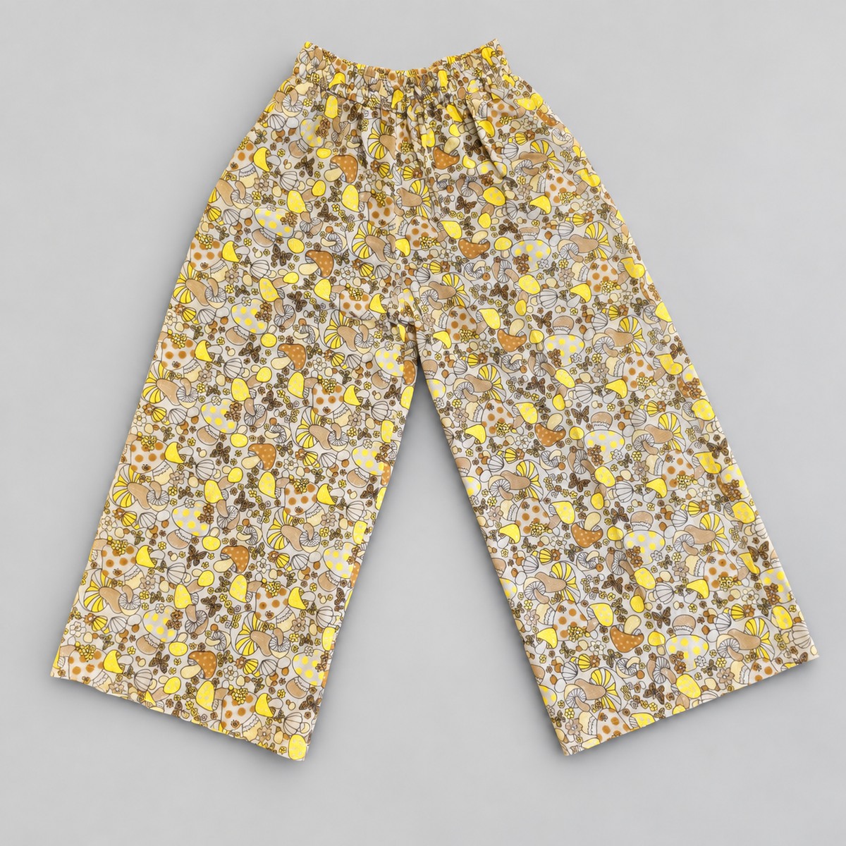 Beige and yellow mushroom print cotton palazzo trousers, front view on soft gray