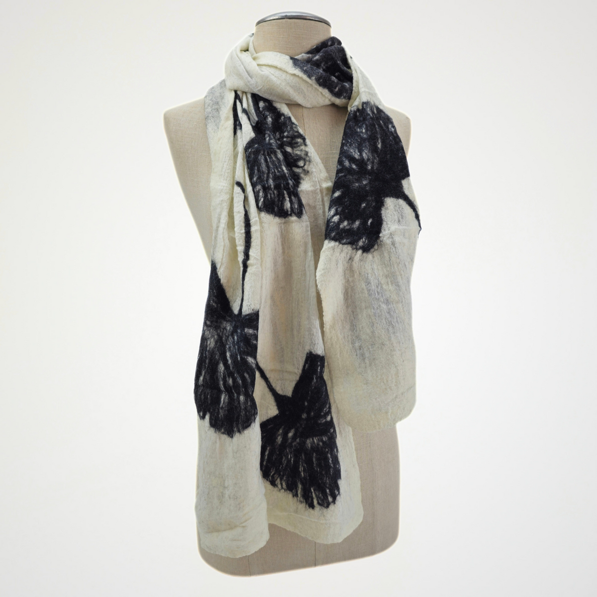 ivory scarf with black ginkgo leaf motifs, looped around a mannequin's neck