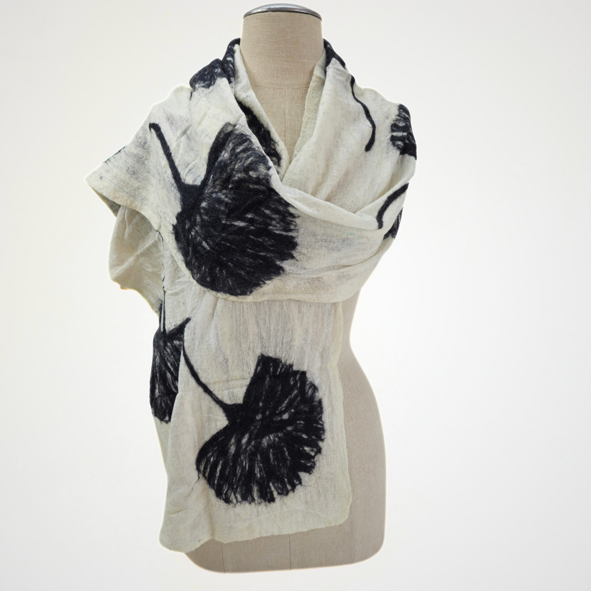 ivory scarf with black ginkgo leaf motifs, wrapped across a mannequin's shoulders