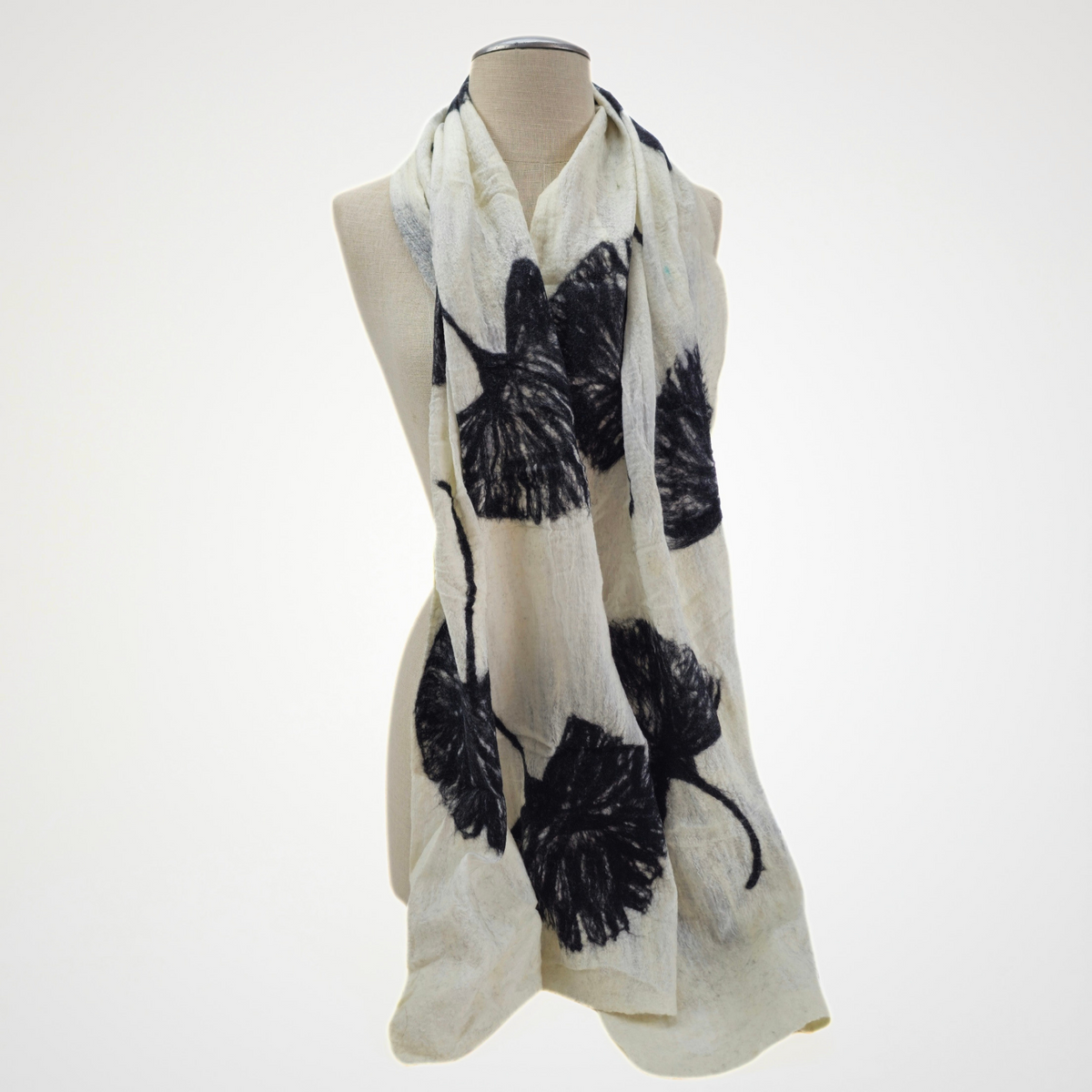 Ivory scarf with black ginkgo leaf motifs draped on a mannequin