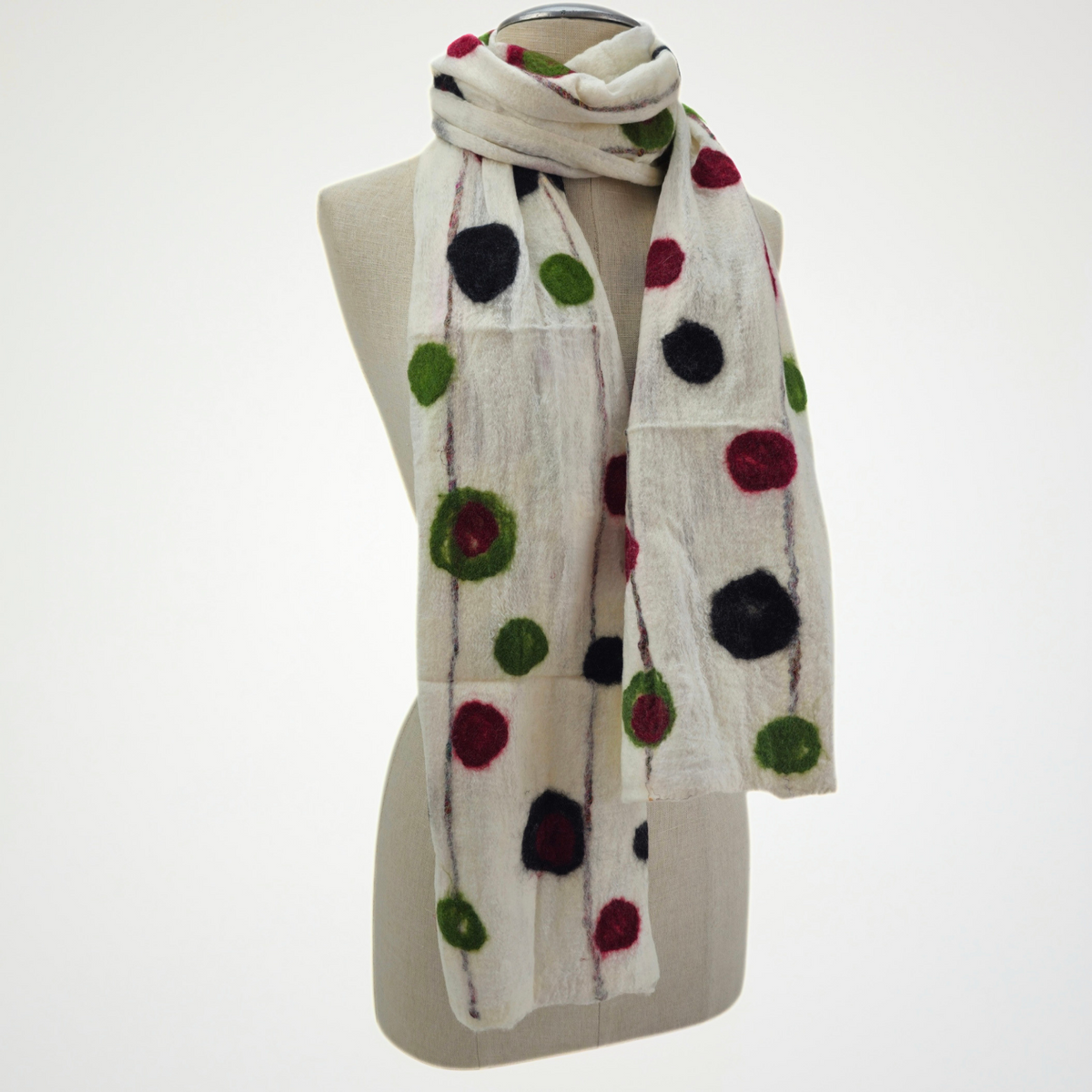 ivory scarf with red, green and black dots and fine vertical lines, looped around a mannequin's neck