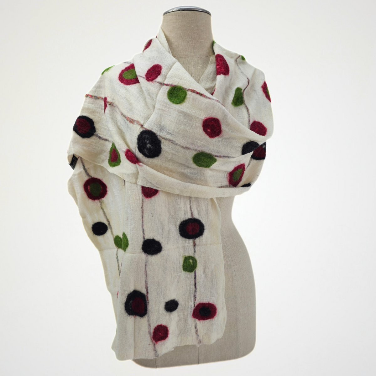 ivory scarf with red, green and black dots and fine vertical lines, wrapped across a mannequin's shoulders