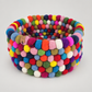 Handmade multicolor wool felt ball basket on Feltiful’s consistent warm soft gray background.