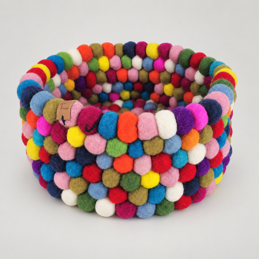 Handmade multicolor wool felt ball basket on Feltiful’s consistent warm soft gray background.