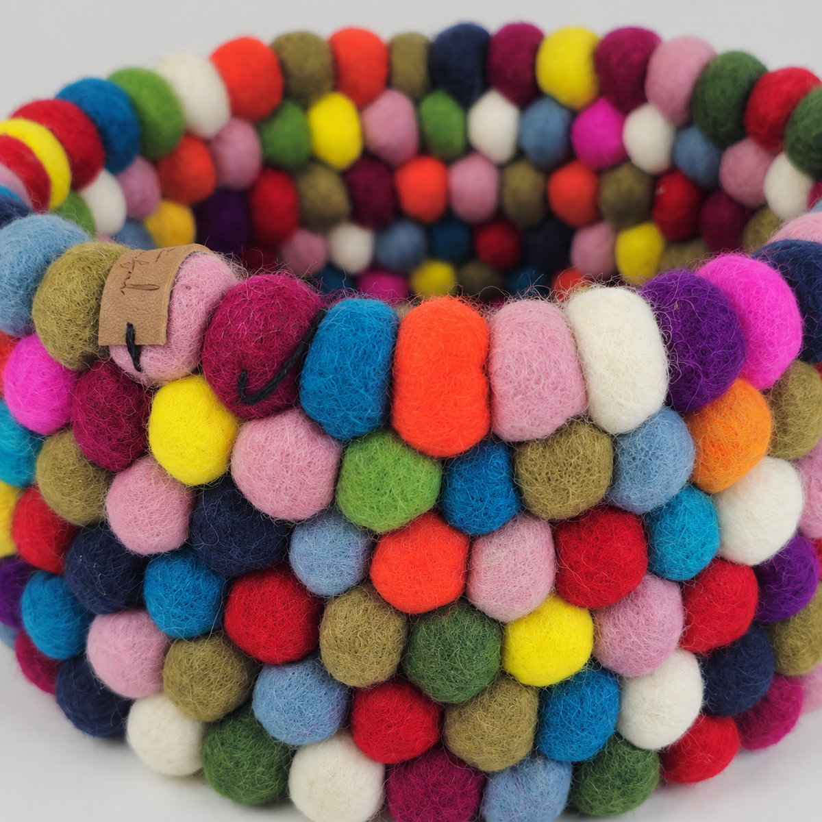 Close-up of the basket’s colorful felt balls, fuzzy texture and hand-stitched joins.