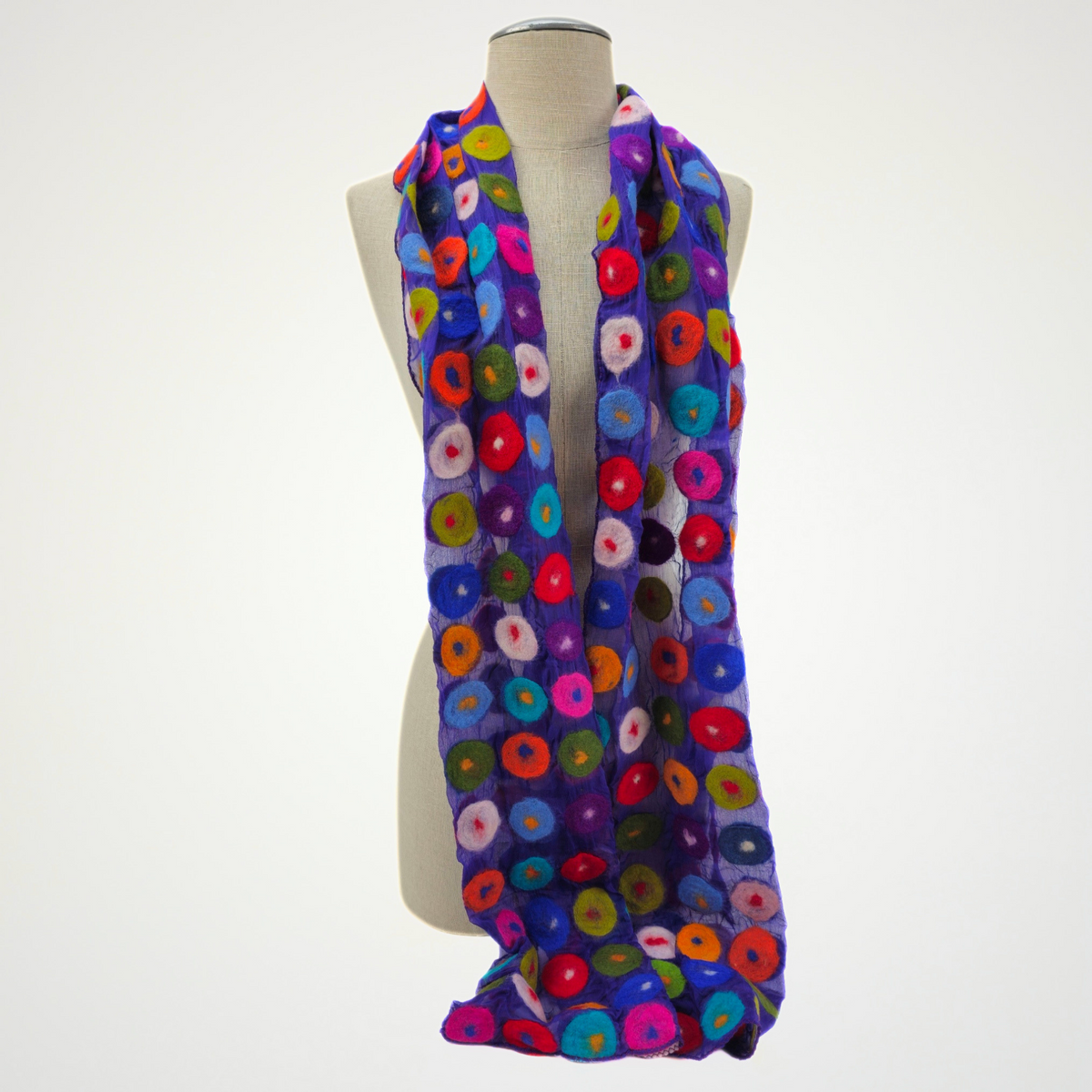 purple scarf covered with multicolored circle motifs, draped on a mannequin