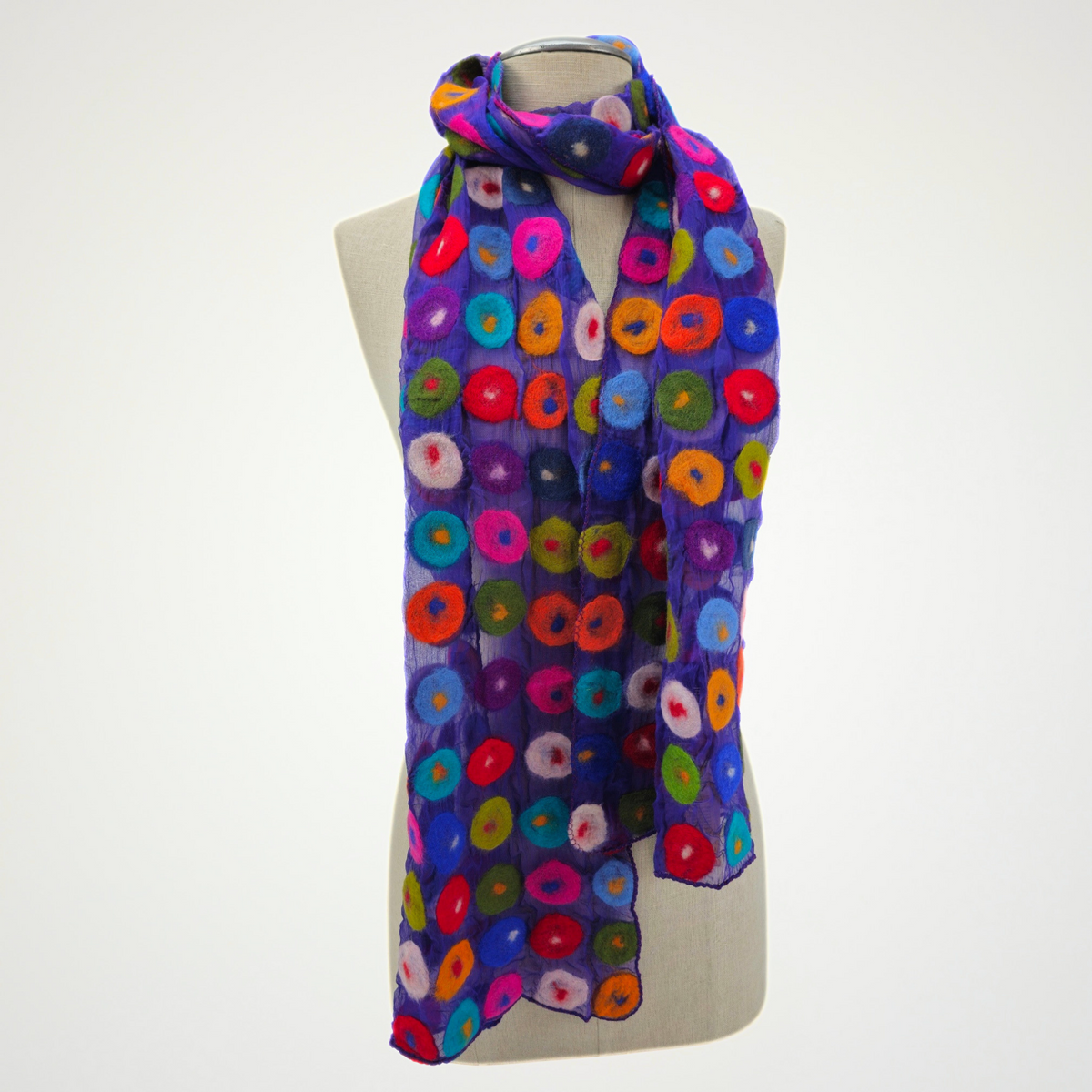 purple scarf covered with multicolored circle motifs, looped around a mannequin's neck